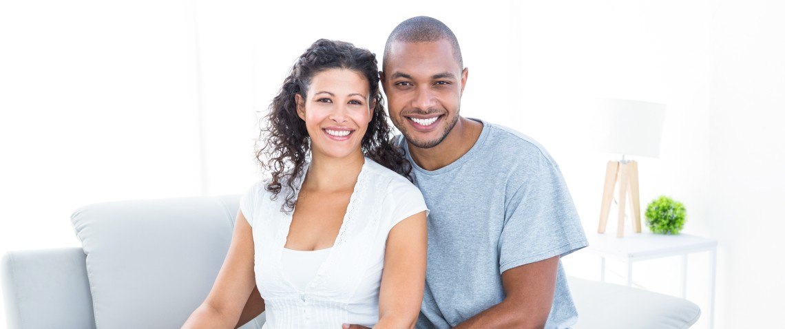 Young couple in their living room, looking at ease and happy.