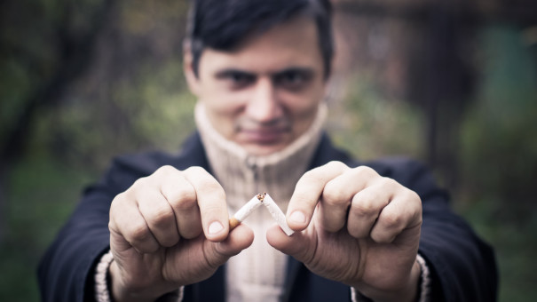 Male looking relieved and determined as he breaks a cigarette in half.