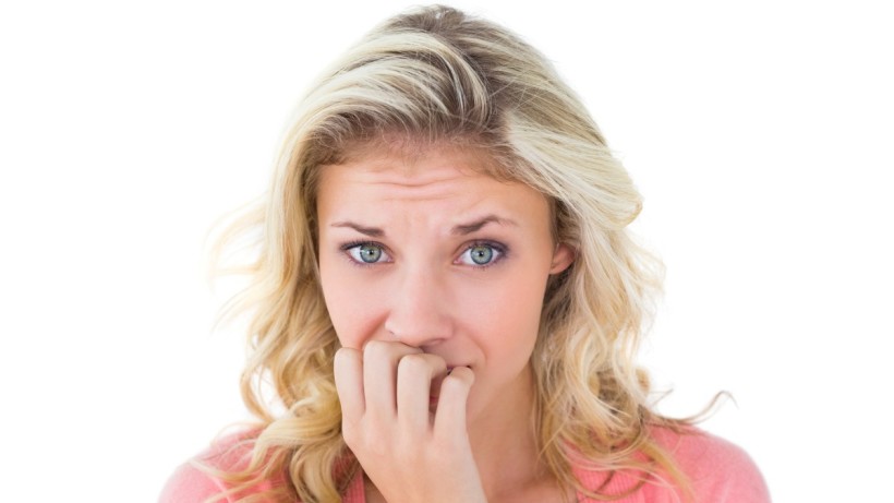 Young woman looks tense, anxious and stressed, as she bites her nails.