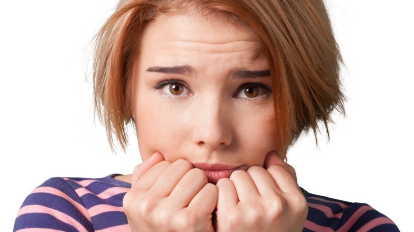 Young woman looking anxious and stressed with clenched hands.