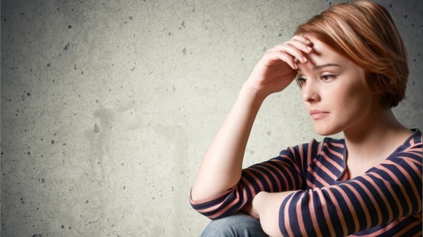 Young woman looking sad, depressed and worried with head resting in hand.